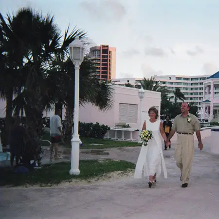 Bride and groom walking hand-in-hand down the 'aisle' to the beach.